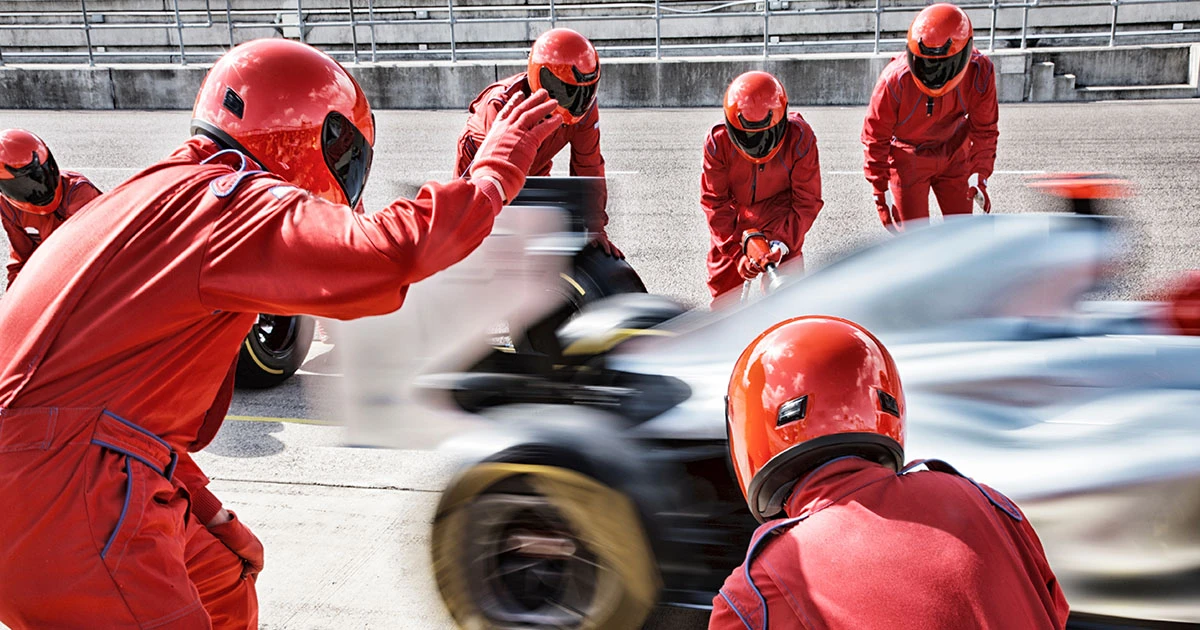 Pitcrew in red uniform assisting a F1 car